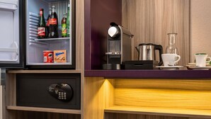 A compact hotel room with a minibar, a safe, a coffee maker, a kettle, and a suitcase. - Mercure Salzburg City (Salzburg)