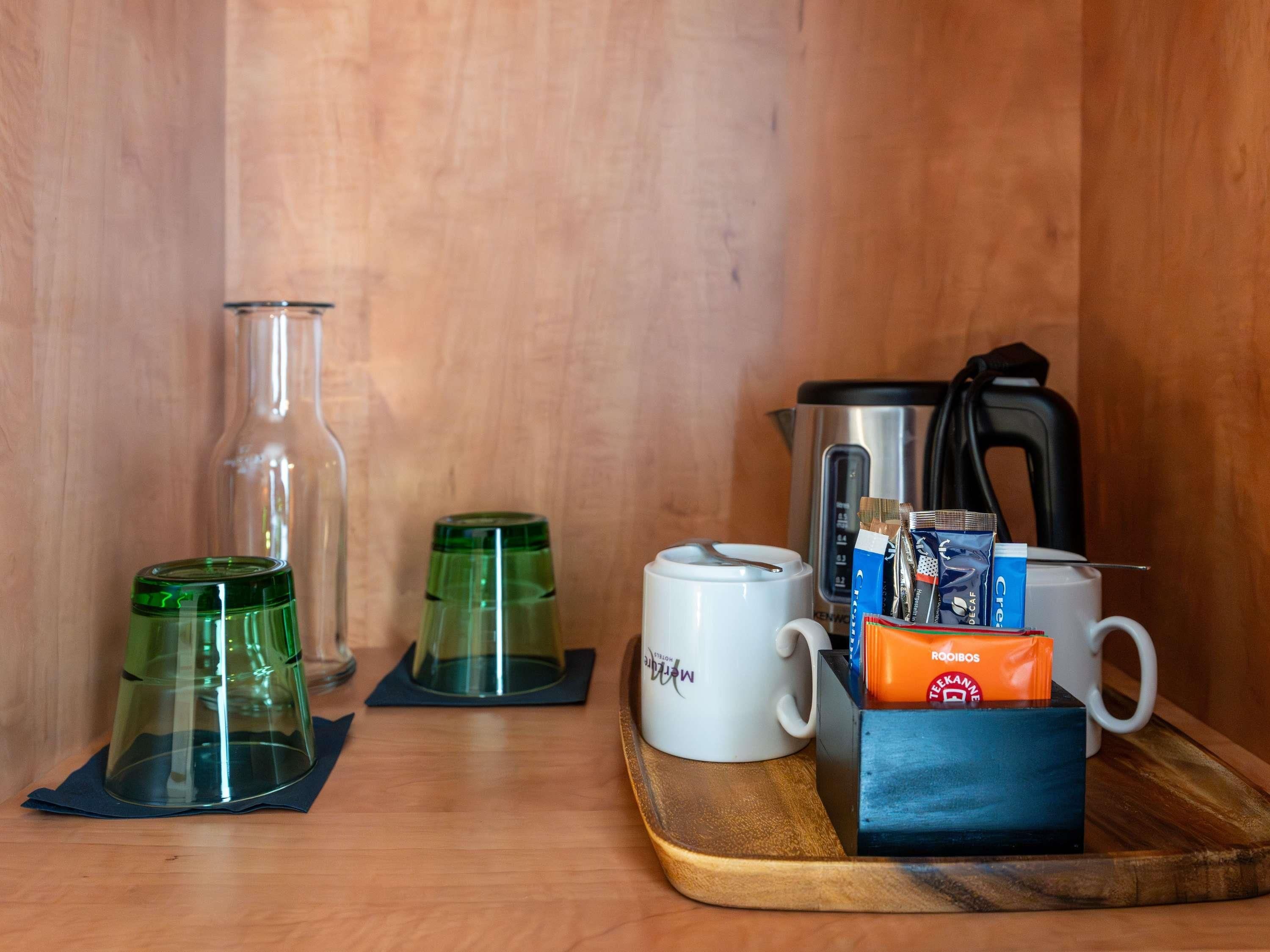 A kitchen area with a coffee maker, a kettle, a mug, and a box of tea bags.