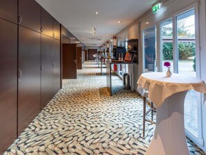 A hotel corridor with a patterned floor, a table with a vase, and a view through the window. - Mercure Salzburg City (Salzburg)