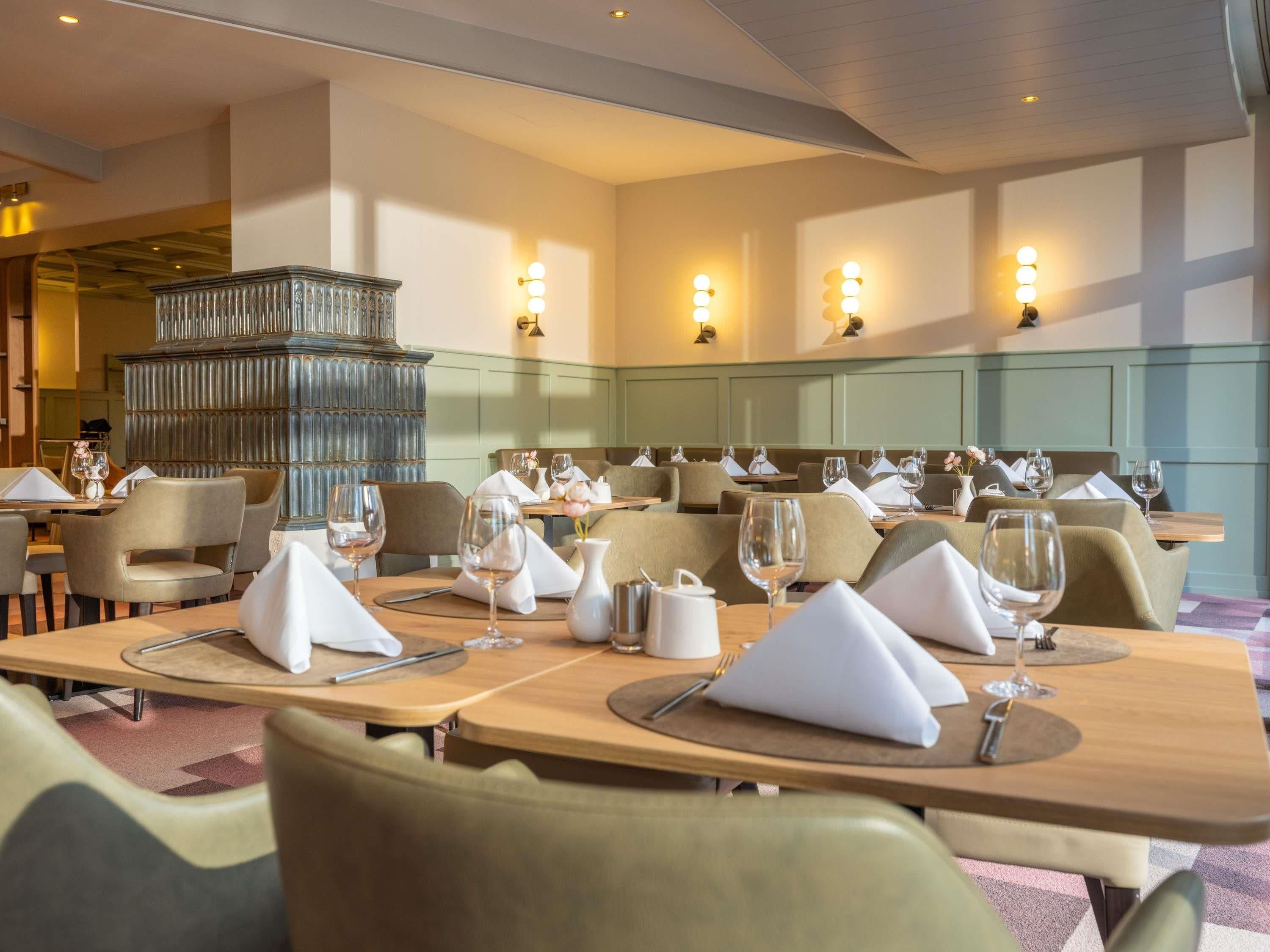Een restaurant met meerdere tafels, elk voorzien van witte servetten, wijnglazen en bestek.