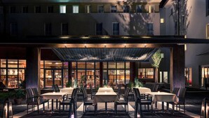 A covered outdoor dining area with tables and chairs, a building with multiple windows, and a clear sky. - Mercure Salzburg City (Salzburg)