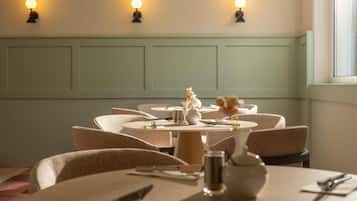 A dining area with round tables, chairs, and wall-mounted lights.