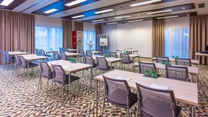 A conference room with tables, chairs, a projector screen, and a Coca-Cola refrigerator. - Mercure Salzburg City (Salzburg)