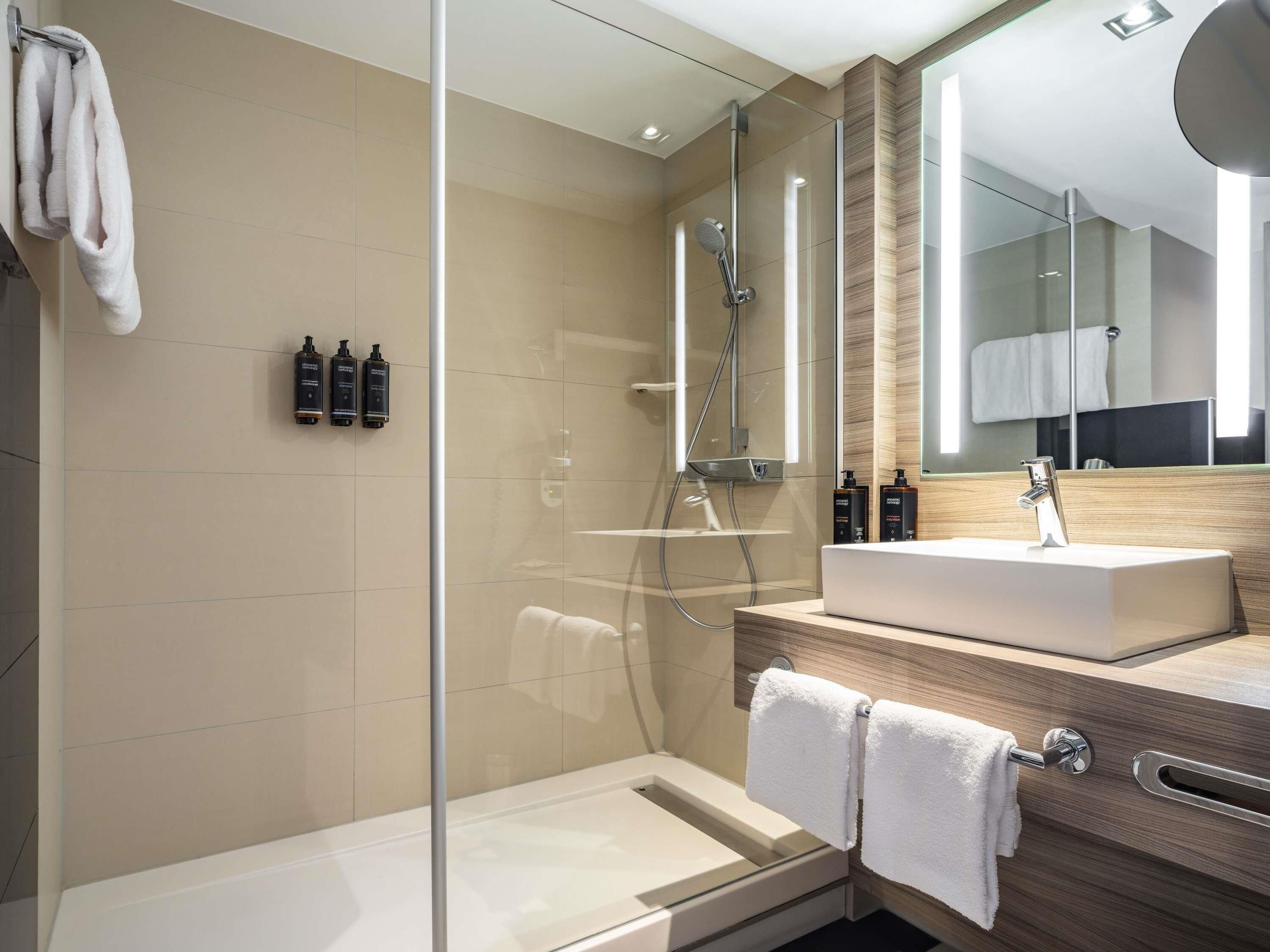 Un bagno moderno con doccia vetrata, un lavabo e uno specchio grande.