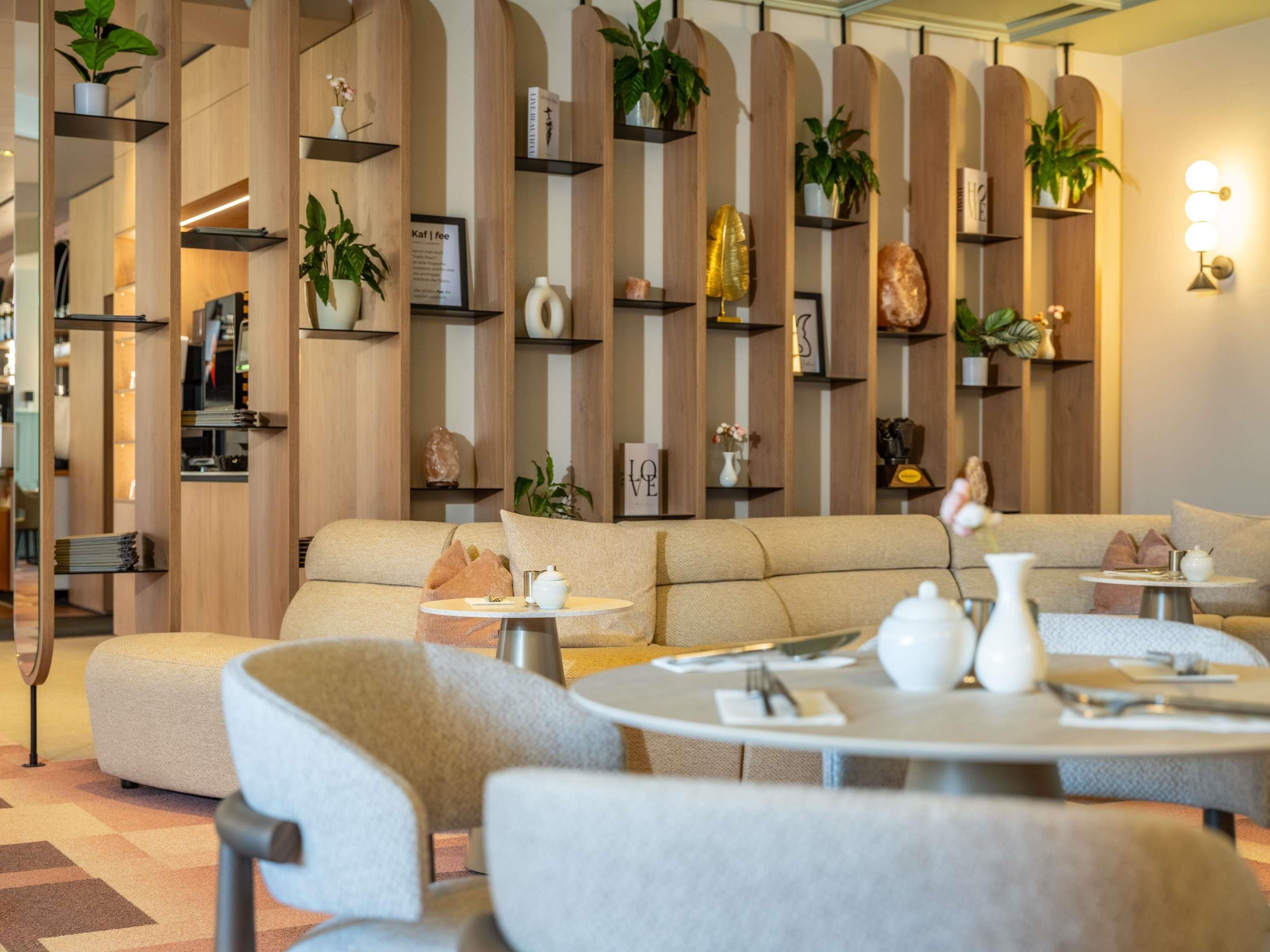 A modern interior with a sofa, round tables, and shelves with plants and decorative items.