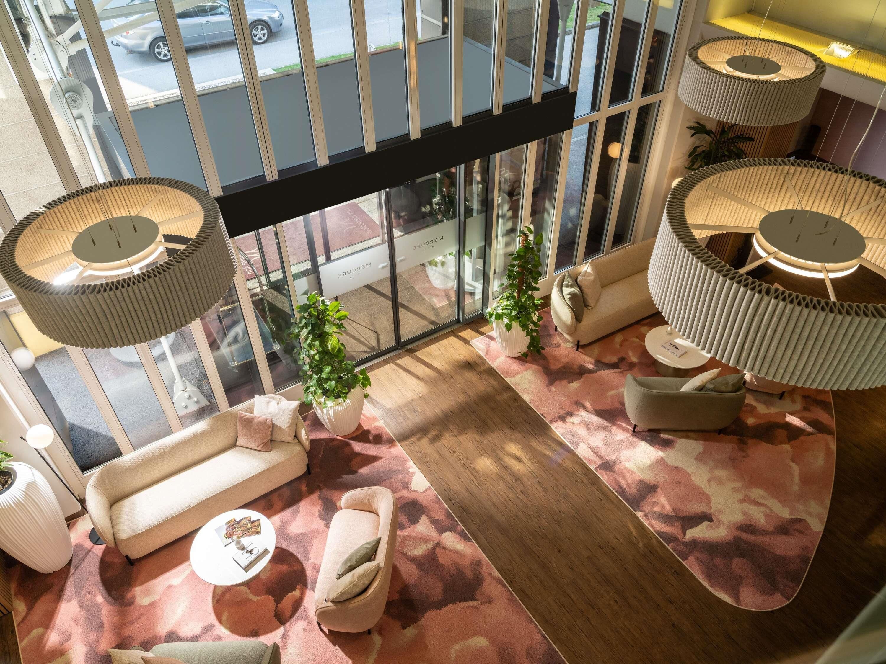 A modern interior with a sofa, armchairs, a coffee table, and a large window with a view of the street.