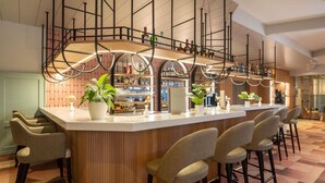 A modern bar area with a curved counter, bar stools, and potted plants. - Mercure Salzburg City (Salzburg)