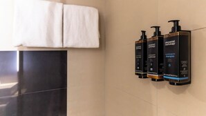 A bathroom with three Elemental Herbology products on the wall and a white towel hanging on a rack. - Mercure Salzburg City (Salzburg)
