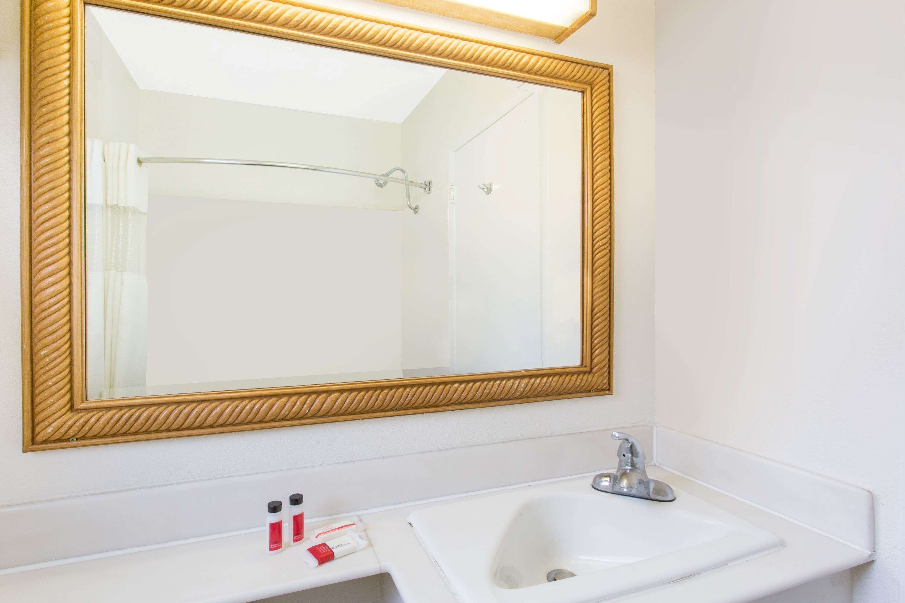 A bathroom with a large mirror, a white sink, and a shower area.