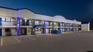 A multi-story motel with a central entrance, a handicap accessible parking area, and a blue neon sign indicating the business is open. - Days Inn by Wyndham Temple (Temple)