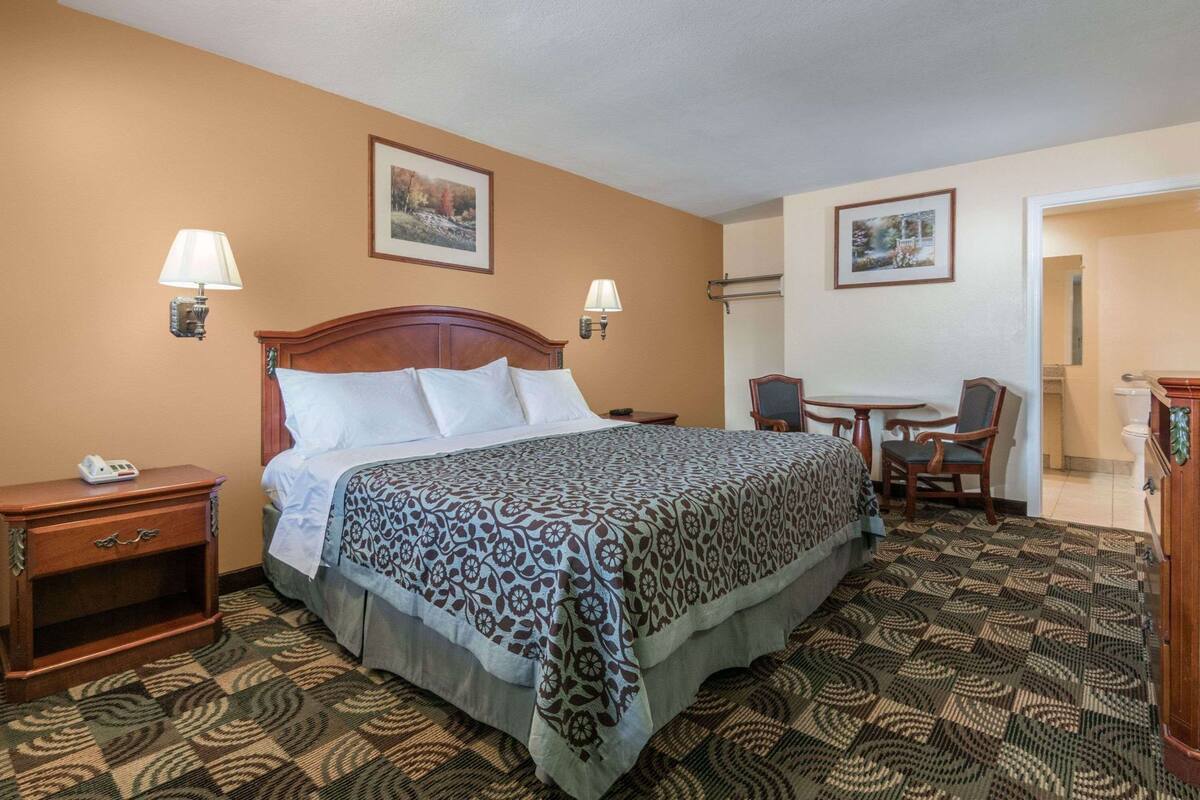 A hotel room with a bed, bedside tables, a desk, and a chair.
