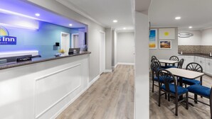 A reception area with a blue sign, a reception desk, and a dining area with blue chairs and a white table. - Days Inn by Wyndham Temple (Temple)