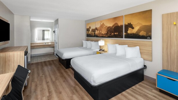 A hotel room with two beds, a desk, a chair, a TV, and a large painting on the wall. - Days Inn by Wyndham Temple (Temple)
