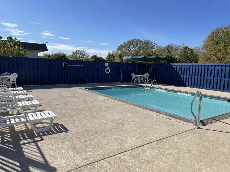 Una piscina con sillas de descanso y una cerca azul.