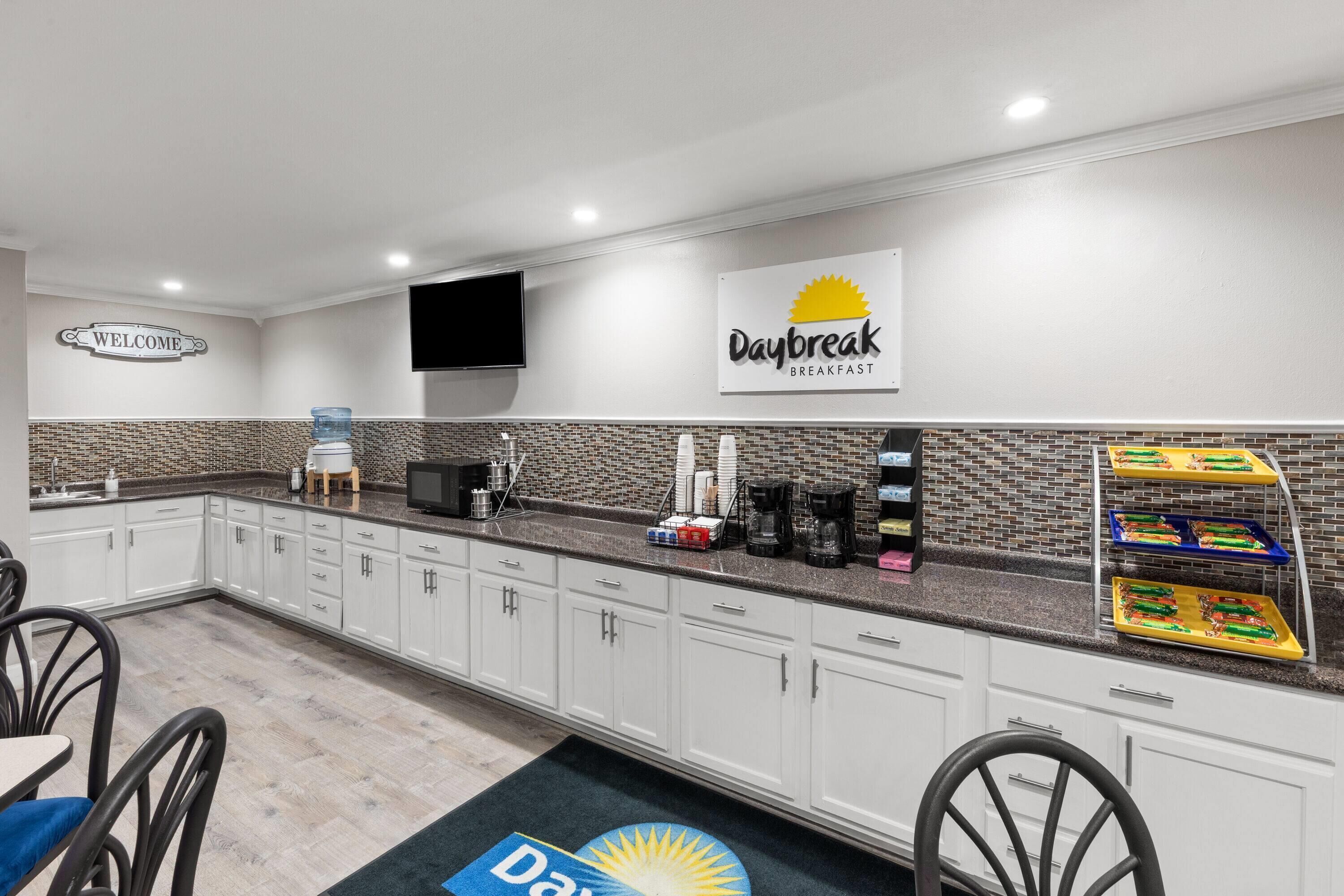 Een hotelkeuken met een bordje 'Daybreak Breakfast', een welkomstbord en een waterdispenser.