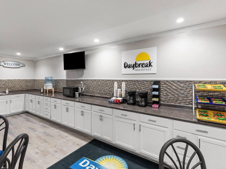 A hotel kitchen with a 'Daybreak Breakfast' sign, a welcome sign, and a water dispenser.