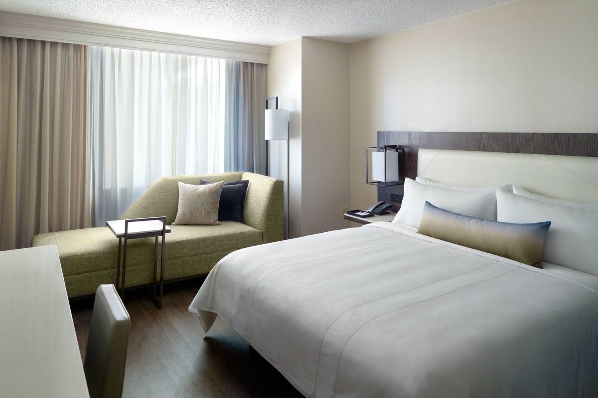 Una habitación de hotel con una cama grande, un sofá, un escritorio y una lámpara.
