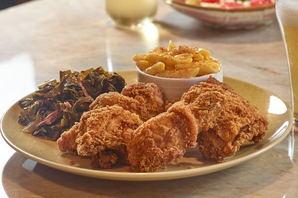 A plate with fried chicken, macaroni, and greens.