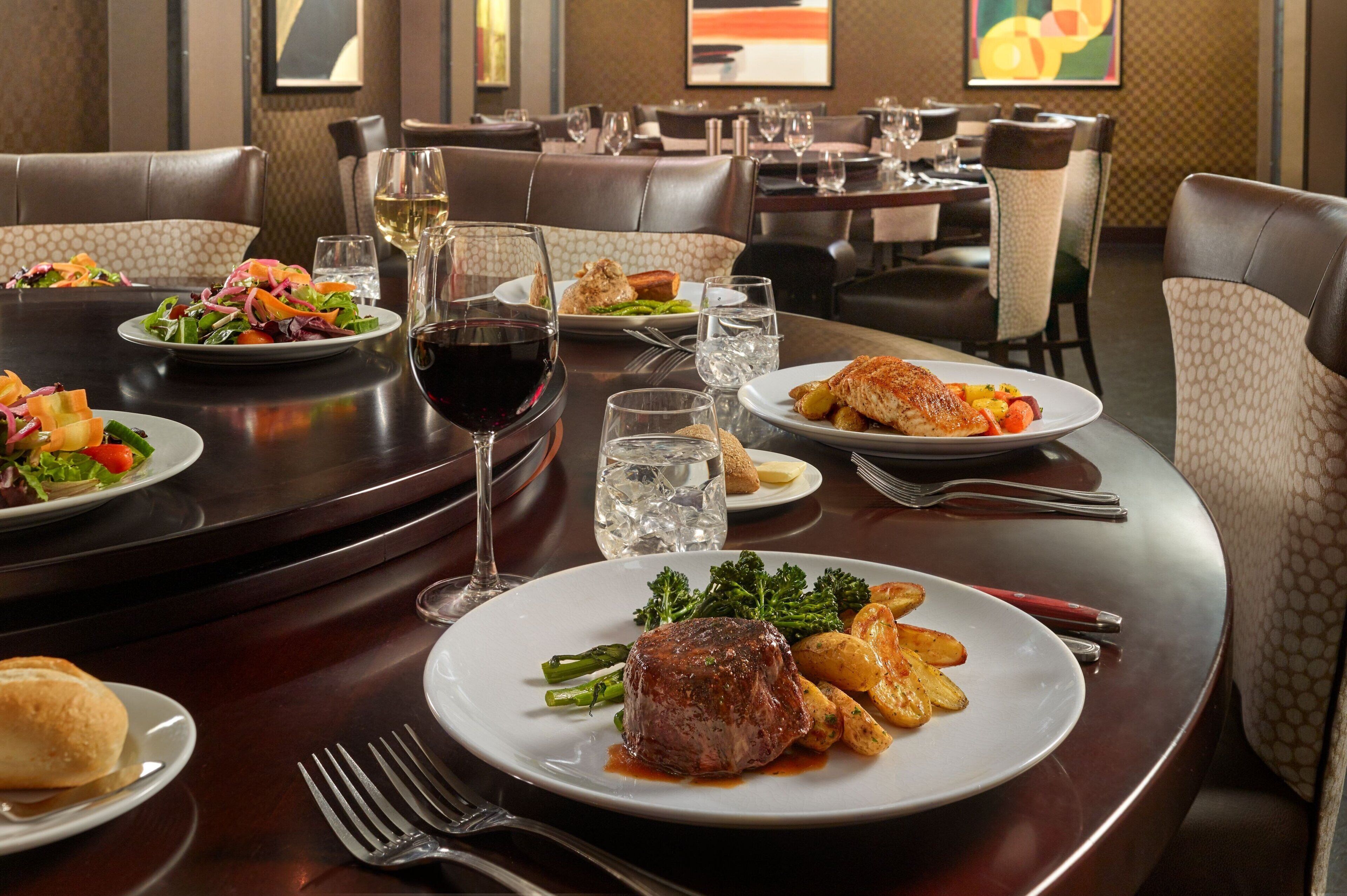 Un comedor con varias mesas, cada una dispuesta con platos de comida, vasos y cubiertos.