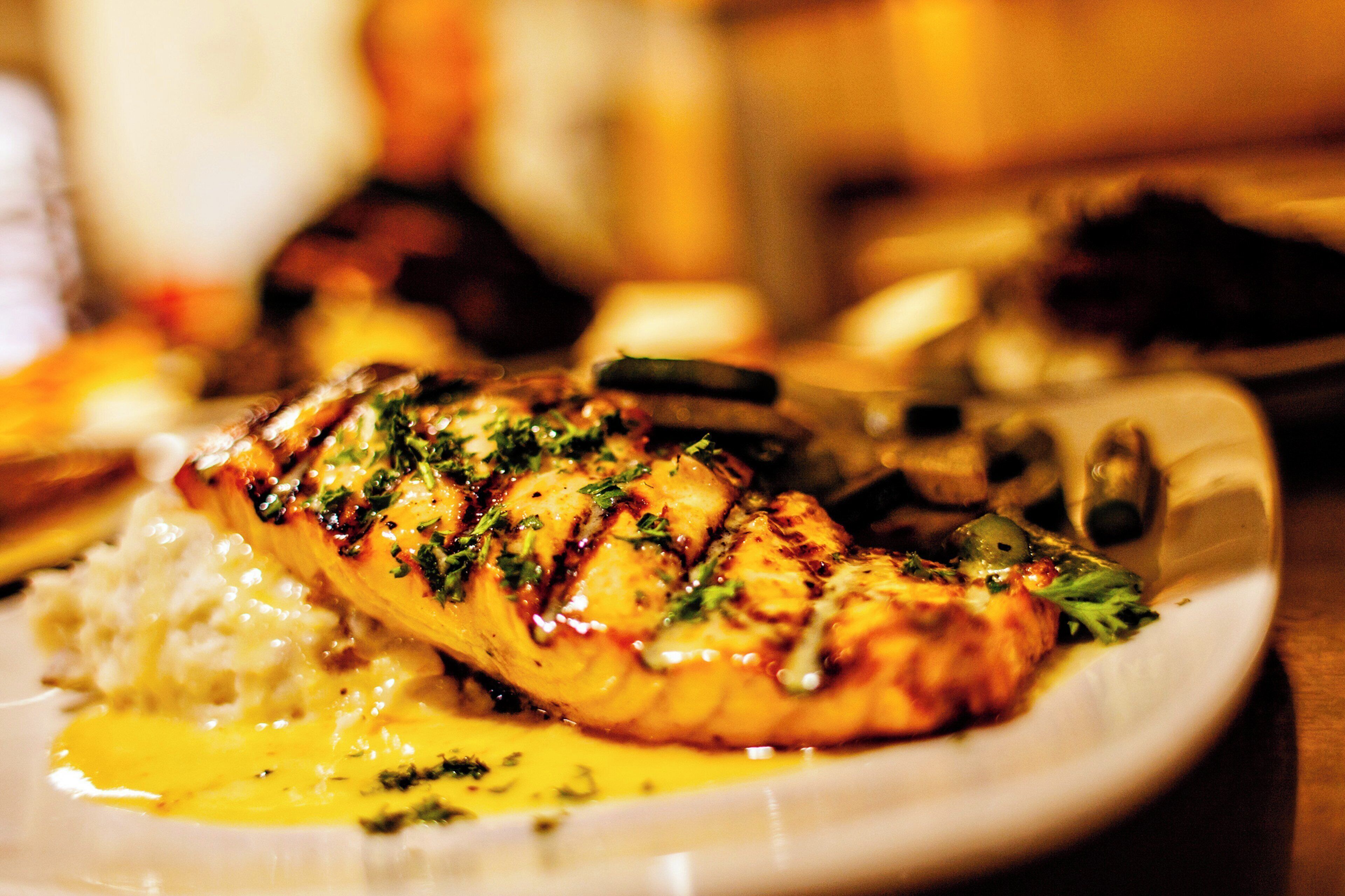 Une assiette contenant un filet de poisson grillé, du riz et une sauce jaune.