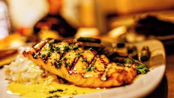 Une assiette contenant un filet de poisson grillé, du riz et une sauce jaune.