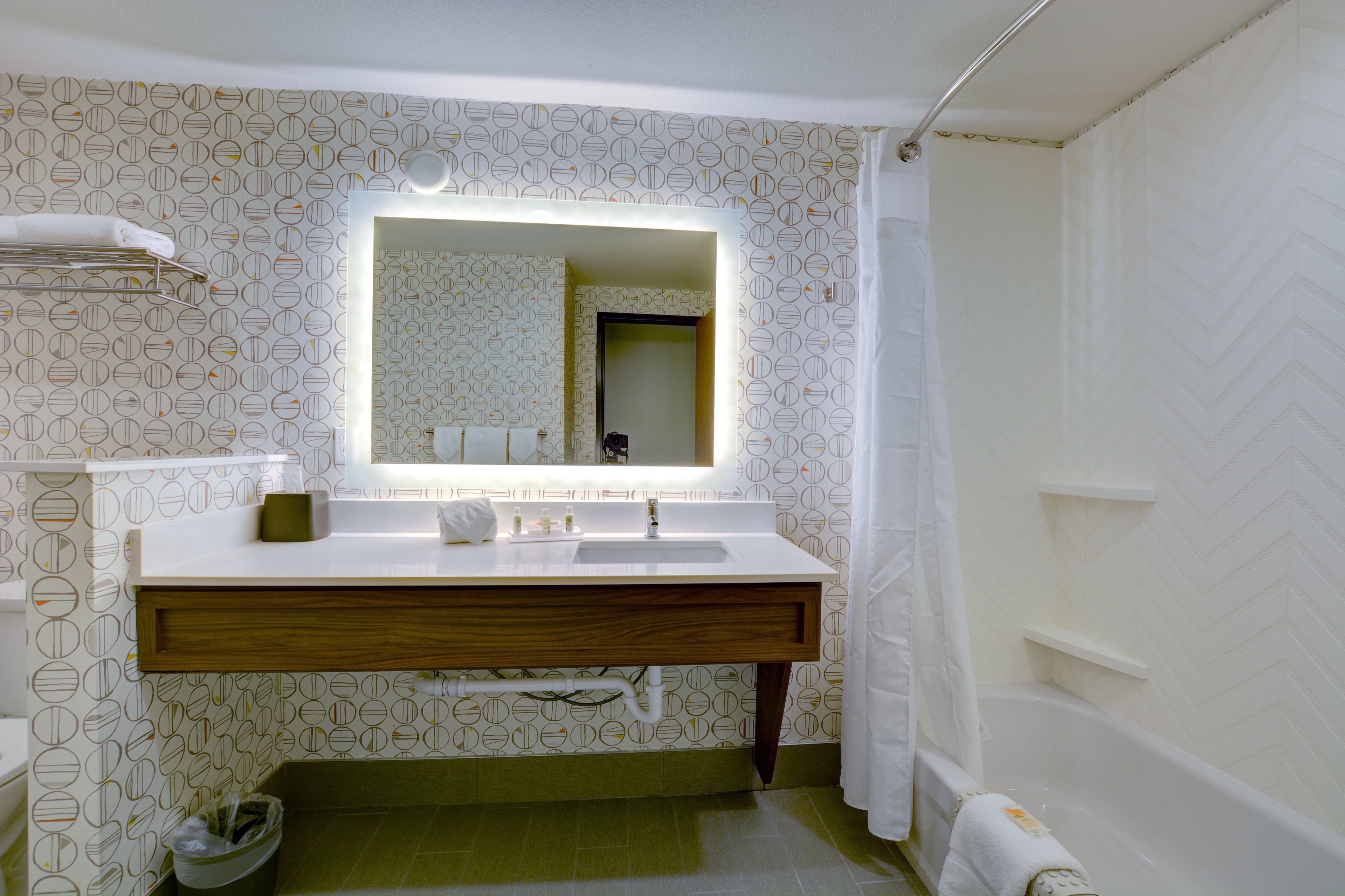 Un baño con lavamanos blanco, espejo y cortina de ducha.