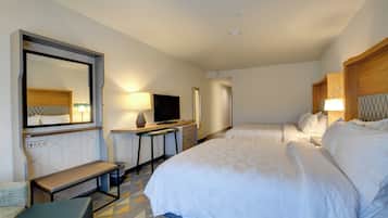 Een hotelkamer met een bed, bureau, televisie en spiegel.