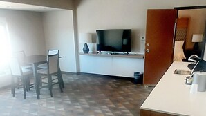 Una camera spaziosa con un tappeto decorato, un tavolo da pranzo con sedie, un televisore e un angolo cottura.