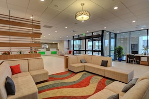 A modern lobby with sofas, a patterned rug, and a reception desk.