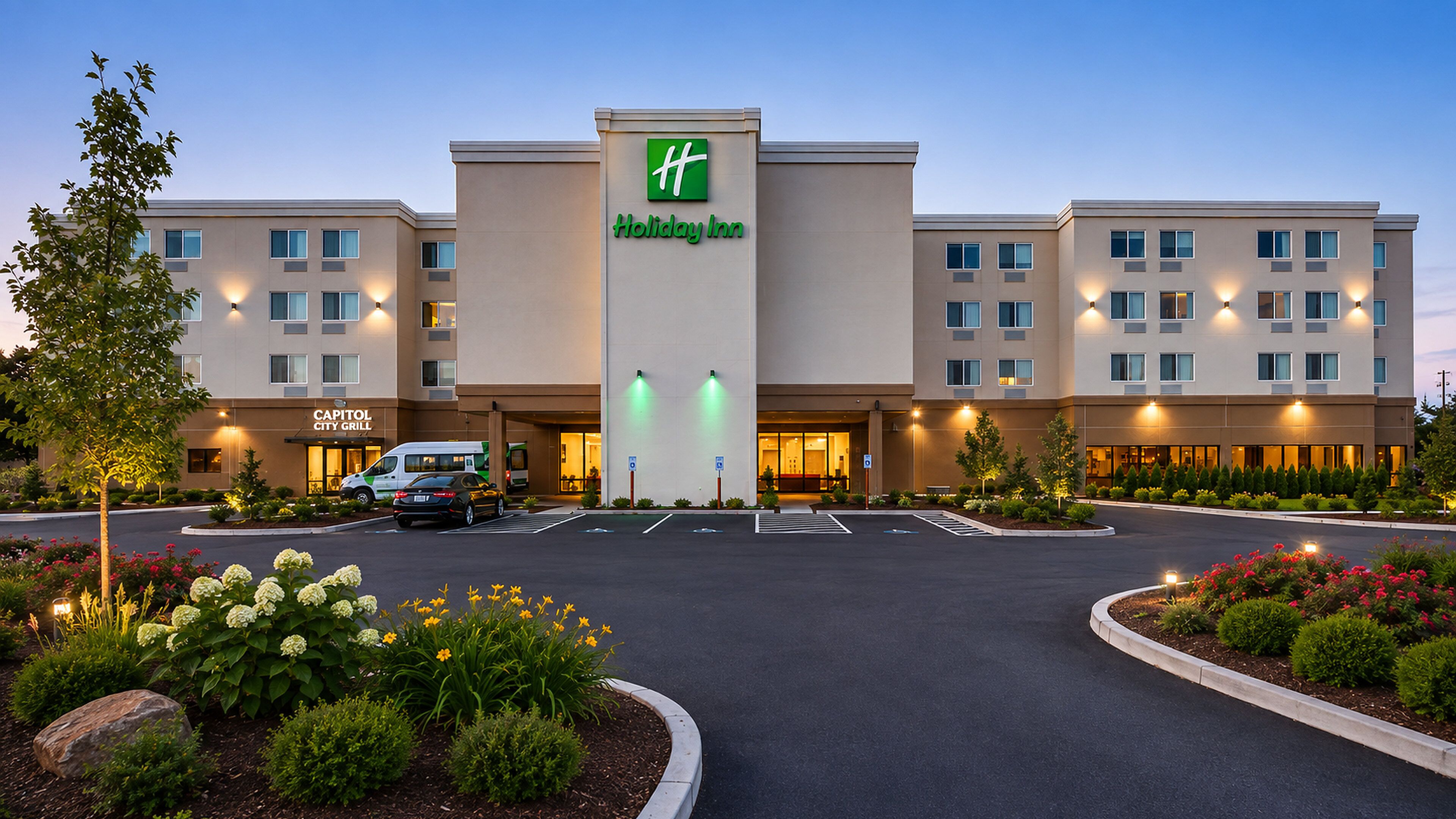A Holiday Inn hotel with a central entrance, a City Grill, and a parking area with landscaping.