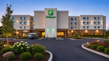 A Holiday Inn hotel with a central entrance, a City Grill, and a parking area with landscaping.