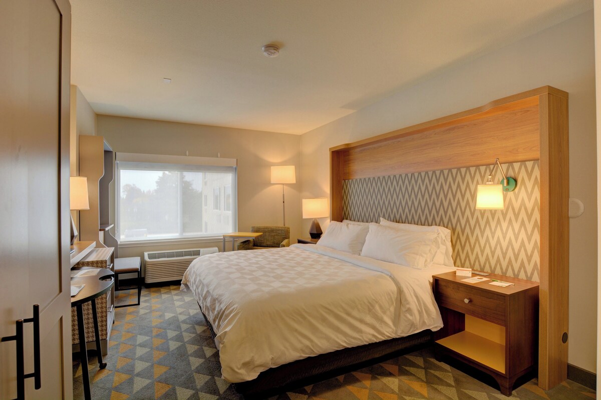 Ein Hotelzimmer mit Bett, Nachttischen, Schreibtisch und Stuhl.