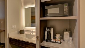 Un bagno d'albergo con lavandino, specchio e macchina per il caffè.