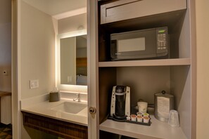 Ein Hotelbad mit Waschbecken, Spiegel und Kaffeemaschine.