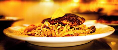A plate of food with a piece of meat and noodles.