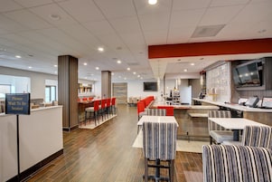 A modern restaurant with a counter, red chairs, striped booths, and a TV mounted on the wall.