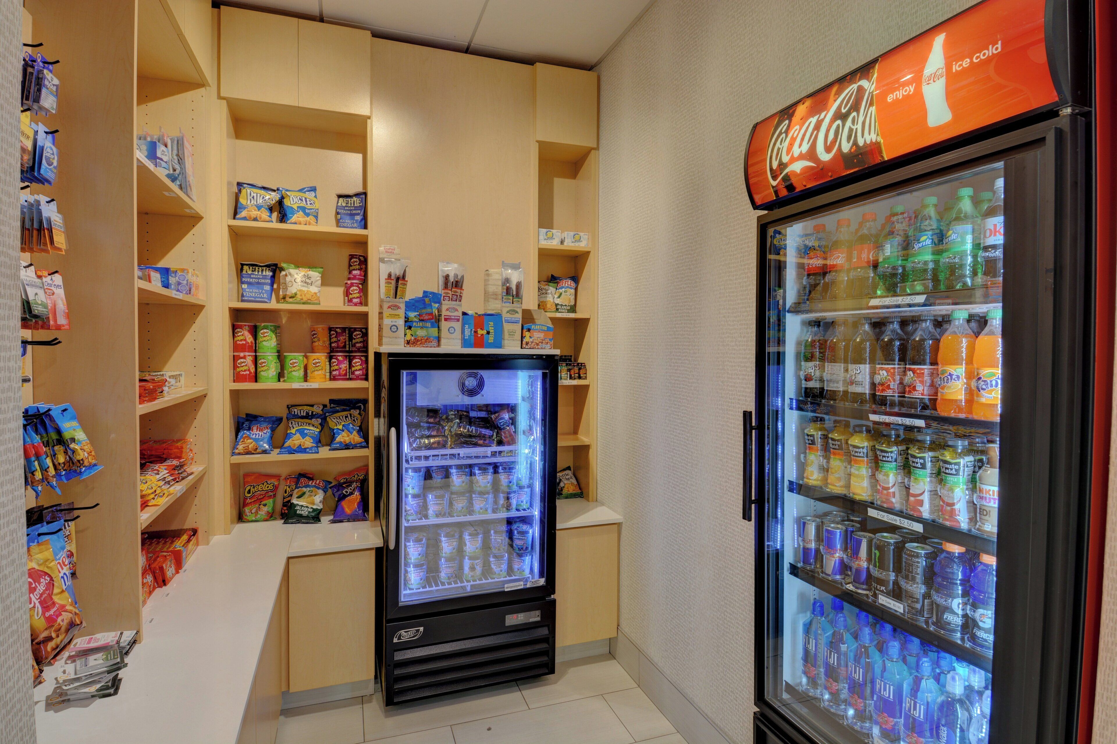 A vending machine area with snacks, a refrigerator stocked with beverages, and a Coca-Cola sign.