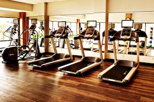 A gym with treadmills, exercise bikes, and a mirrored wall.