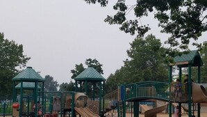 Un'area giochi con scivoli e strutture per arrampicata, immersa nel verde.