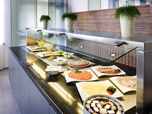 A buffet with various food items, including seafood, salads, and desserts, displayed on a glass counter with a modern design. - Mercure Hotel München Süd Messe (Munich)