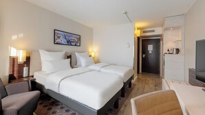 Een hotelkamer met een groot bed, een bureau, een stoel, een televisie en een schilderij aan de muur.