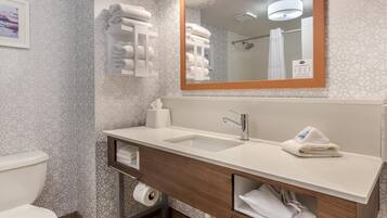 Un baño moderno con un lavamanos blanco, un espejo con marco de madera y un perchero con toallas dobladas.
