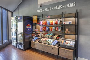 A snack display with various chips and snacks, a Pepsi refrigerator, and a sign indicating treats. - Hampton Inn New Bern (New Bern)
