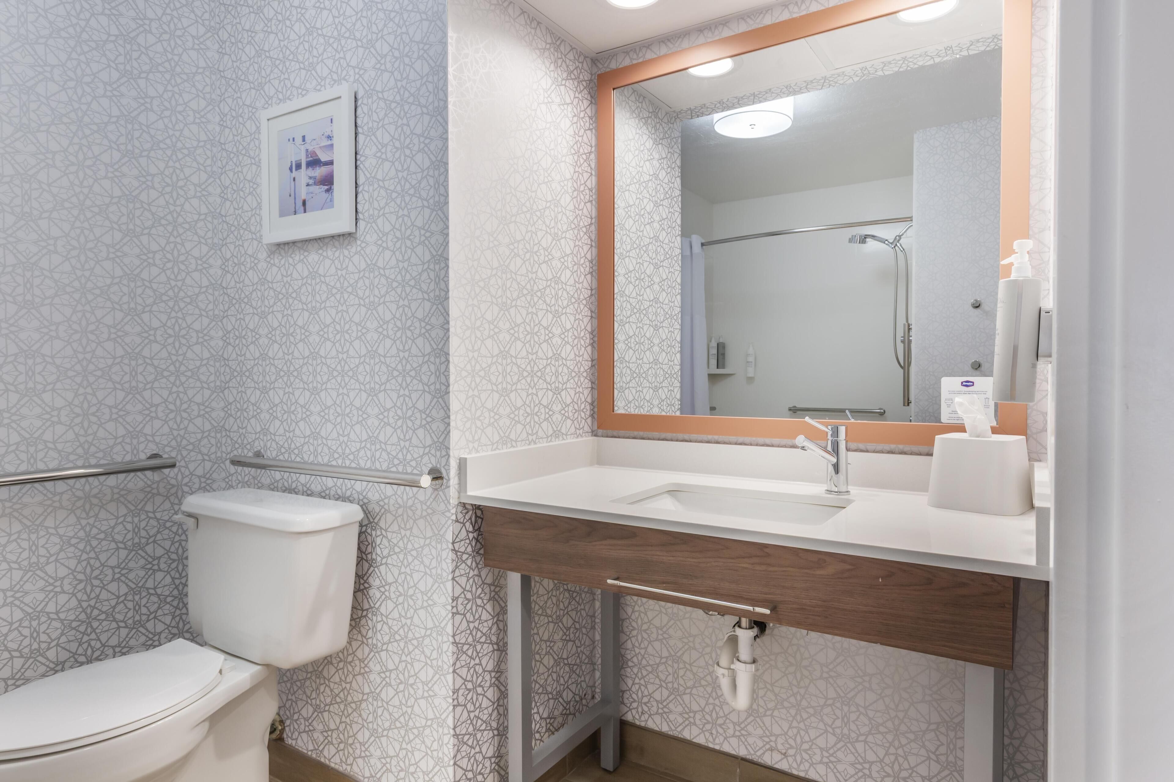 Un bany modern amb vàter, un lavabo amb mirall i plat de dutxa.