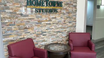 A reception area with a stone wall, two red chairs, and a small round table.