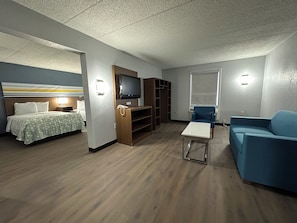 A hotel room with a bed, a TV, a blue sofa, a small table, and a wardrobe.