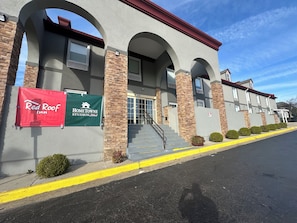 A building with a red and green banner advertising Red Roof Inn and HomeTowne Studios. - HomeTowne Studios by Red Roof Richmond, VA - W Broad St (Richmond)