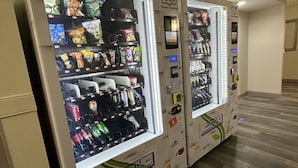 A row of vending machines stocked with snacks and beverages. - HomeTowne Studios by Red Roof Richmond, VA - W Broad St (Richmond)
