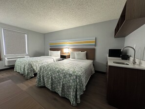 A hotel room with two beds, a large window, a wall-mounted TV, and a kitchenette. - HomeTowne Studios by Red Roof Richmond, VA - W Broad St (Richmond)