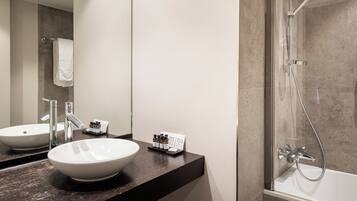 Une salle de bain moderne avec un grand lavabo blanc, un miroir et une douche séparée par une paroi de verre.